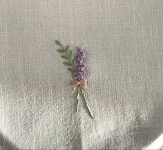 a small purple flower on a white cloth