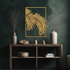 a table with vases and plants on it in front of a green painted wall