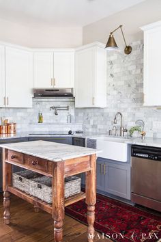 a kitchen with an island in the middle and white cabinets on the other side,