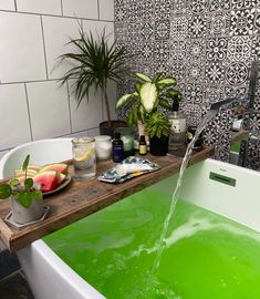 a bath tub filled with green liquid next to plants