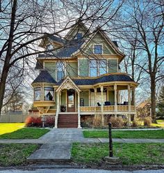 a large yellow house with lots of windows on the front and second story, surrounded by trees