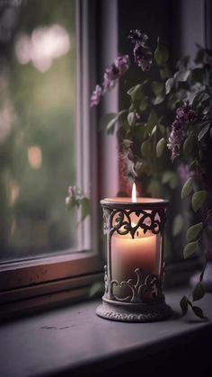 a lit candle sitting on top of a window sill