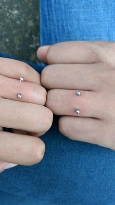 two women's hands with three different rings on their fingers and one is wearing a blue shirt