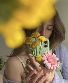 a woman taking a selfie with her cell phone and flowers in front of her