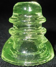 a green glass vase sitting on top of a black table