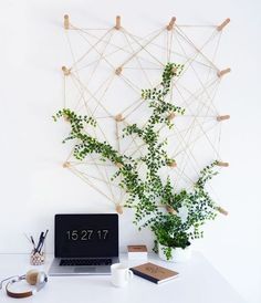 a laptop computer sitting on top of a white desk next to a plant and headphones