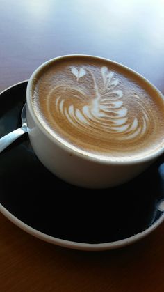 a cappuccino on a black saucer with white designs in the foam