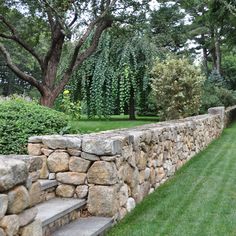 a stone wall in the middle of a grassy area