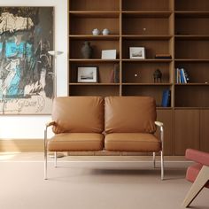 a brown leather couch sitting in front of a book shelf