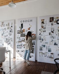 a woman standing in front of a wall with pictures on it and writing on the wall