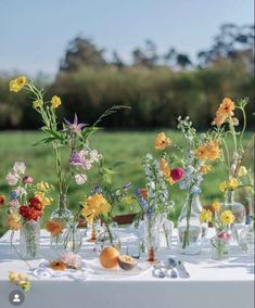 several vases filled with flowers sitting on top of a white cloth covered tablecloth