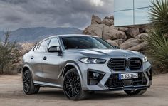 a silver bmw suv parked in front of some rocks