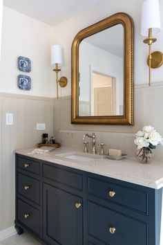 a bathroom vanity with two sinks and a large gold framed mirror over it's top