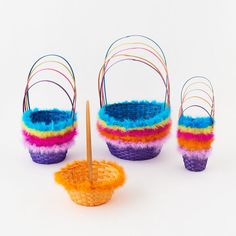 three baskets with colorful yarn and wooden sticks