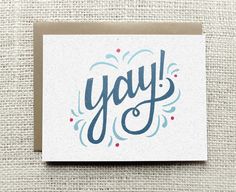 a greeting card with the word yay on it in blue and red ink, against a beige background