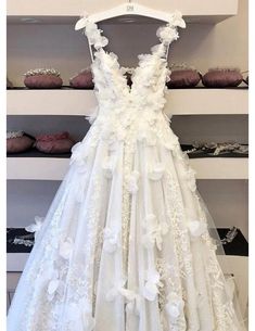 a white wedding dress hanging on a rack in front of shelves with cakes and cupcakes