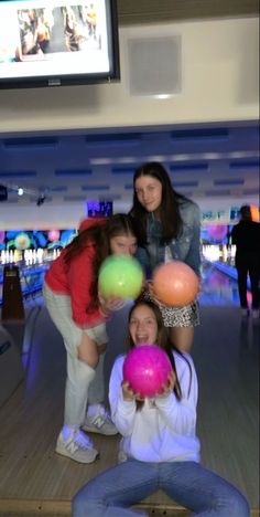 three girls playing with balls in a bowling alley