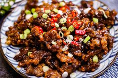 a white plate topped with meat covered in sauce and toppings on top of a blue and white table cloth