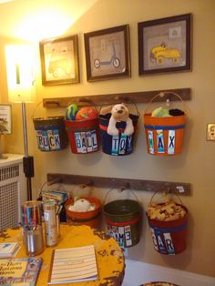 there are many buckets on the wall with pictures above them and other things in baskets