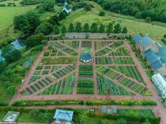 an aerial view of a vegetable garden in the middle of a field with buildings and trees