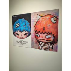 two posters hang on the wall in an art gallery, each with different faces and hair styles