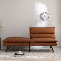 a living room with a couch, clock and lamp on the wall next to it