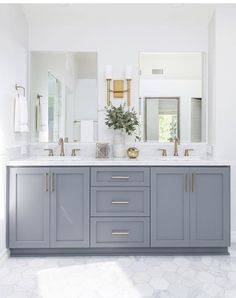 a bathroom with two sinks, mirrors and gold accents on the countertop in front of a large mirror