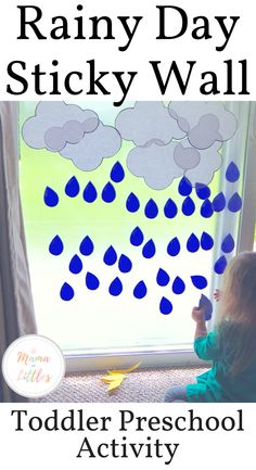 a toddler sitting in front of a window with rain drops on it and the words rainy day sticky wall