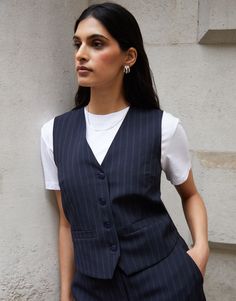 Elevate your style with our chic pinstripe fitted waistcoat, perfect to hit the soft tailoring trend that's everywhere this year. With a v-neck opening and button fastening, you can add a sophisticated modern edge to any outfit whether you wear it as a standalone statement piece or as a layer over t-shirts or dresses. Complete with front darts at the bust for a classic and tailored silhouette. Pair with a white t-shirt, denim jeans and trainers for a casual look, or pair with tailored trousers, Fitted Waistcoat, Tailored Waistcoat, Soft Tailoring, Co Ord, Trousers, V Neck