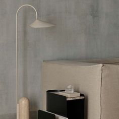 a table lamp sitting on top of a wooden floor next to a book shelf and end table