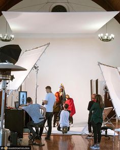 several people are standing in front of white backdrops with lights on them and one person is taking a photo