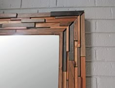 a wooden mirror hanging on the wall next to a brick wall