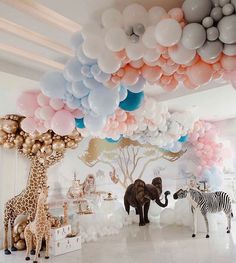 an elephant, zebra and giraffe are standing in front of balloons on the ceiling