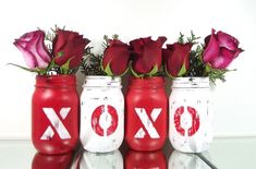 three painted jars with roses in them sitting on a table