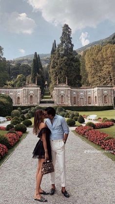 a man and woman kissing in front of a garden