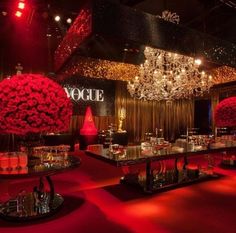 a red carpeted room with chandeliers and flowers on the tables in front of it