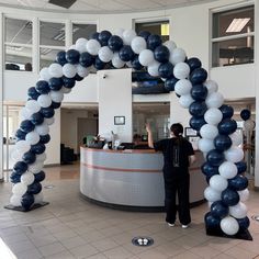 a man standing in front of a white and blue balloon arch