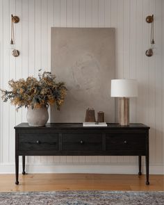 a black table with two vases on it and a painting hanging over the top