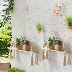 three hanging planters with plants on them against a white brick wall in front of a house