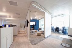 an office with white walls and wood flooring is seen through the glass door to another room