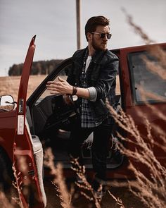 a man sitting in the back of a red truck with his hand out to someone