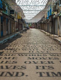 an alley way with words written on the pavement and buildings in the background, all lined up