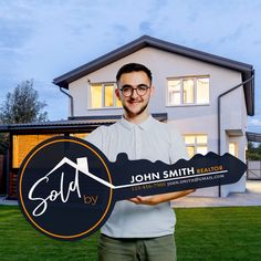 a man holding up a real estate sign in front of a house with the words sold written on it