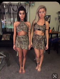 two women dressed in animal print outfits standing next to each other with makeup on their faces