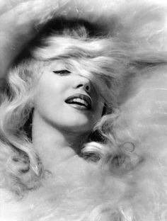 a black and white photo of a woman with her hair blowing in the wind