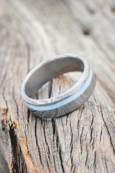 a silver ring sitting on top of a wooden table next to a piece of wood