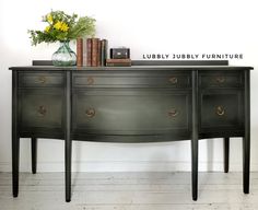 a black dresser with three drawers and flowers on top