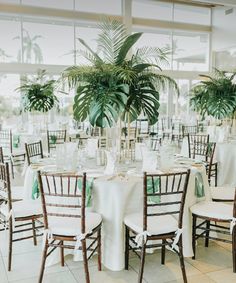 the tables are set with white linens and palm trees