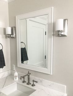 a white bathroom sink sitting under a mirror next to a wall mounted faucet