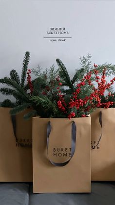 three brown paper bags sitting on top of a couch next to red berries and greenery